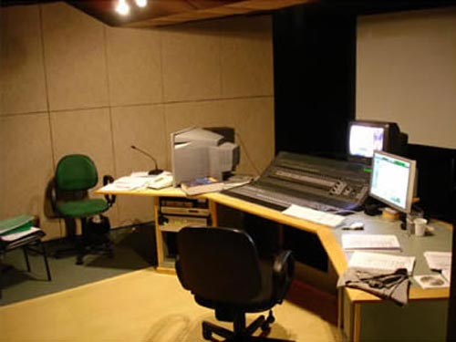 Sala de controle com mesa de som e monitores